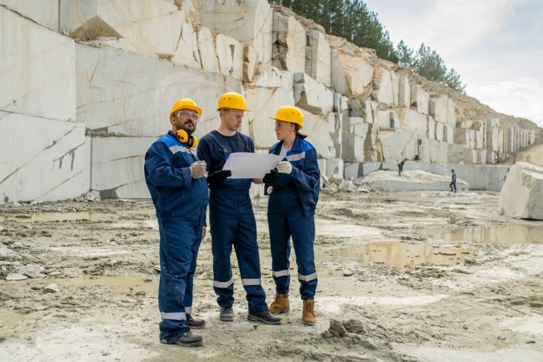 Team of miners in workwear discussing blueprint